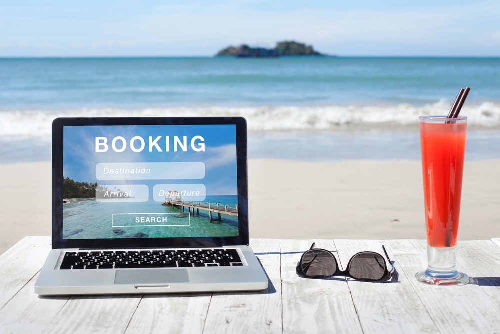laptop showing booking site on beach