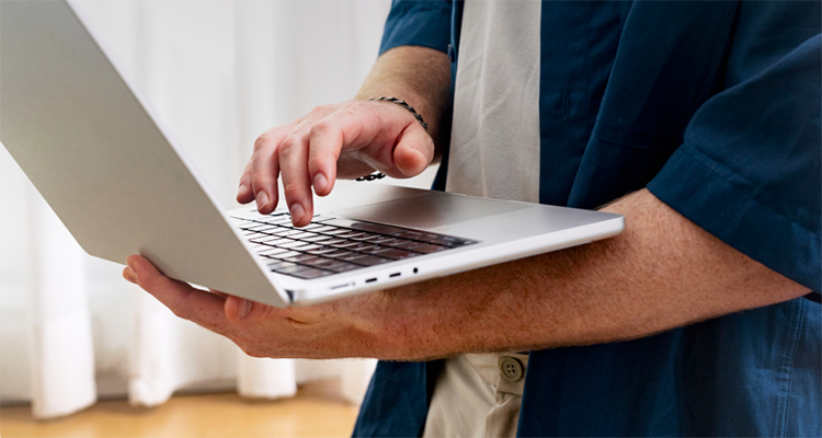 A close-up view of a person's hands typing on a silver laptop keyboard.